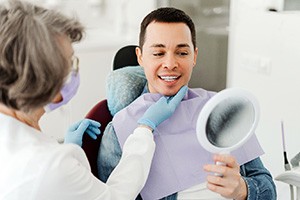 Man smiling at reflection in mirror with dentist
