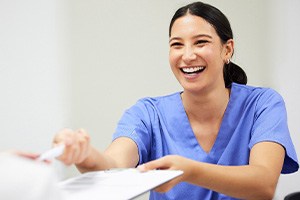 Dental assistant smiling while handing patient form