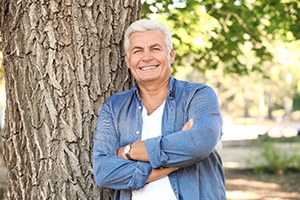 Man smiling outside wearing implant-retained dentures in Oakton