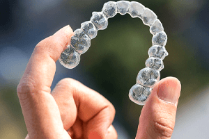 a person holding an Invisalign aligner in Oakton