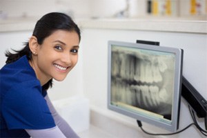 Dental assistant smiling while looking at patient's X-ray