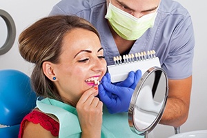 woman in red shirt trying on veneers in dental chair 