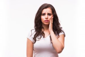 woman holding her jaw in pain