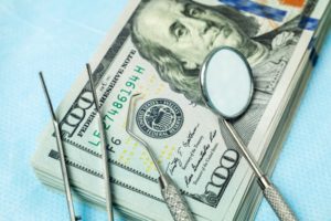 dental tools sitting on a pile of money