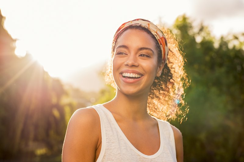 a young woman standing outside enjoying the weather and showing off her smile