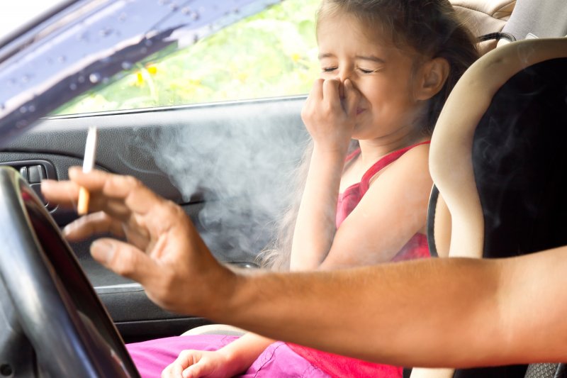 young girl plugging nose around secondhand smoke