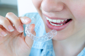 Close-up of person in blue shirt putting in Invisalign aligner
